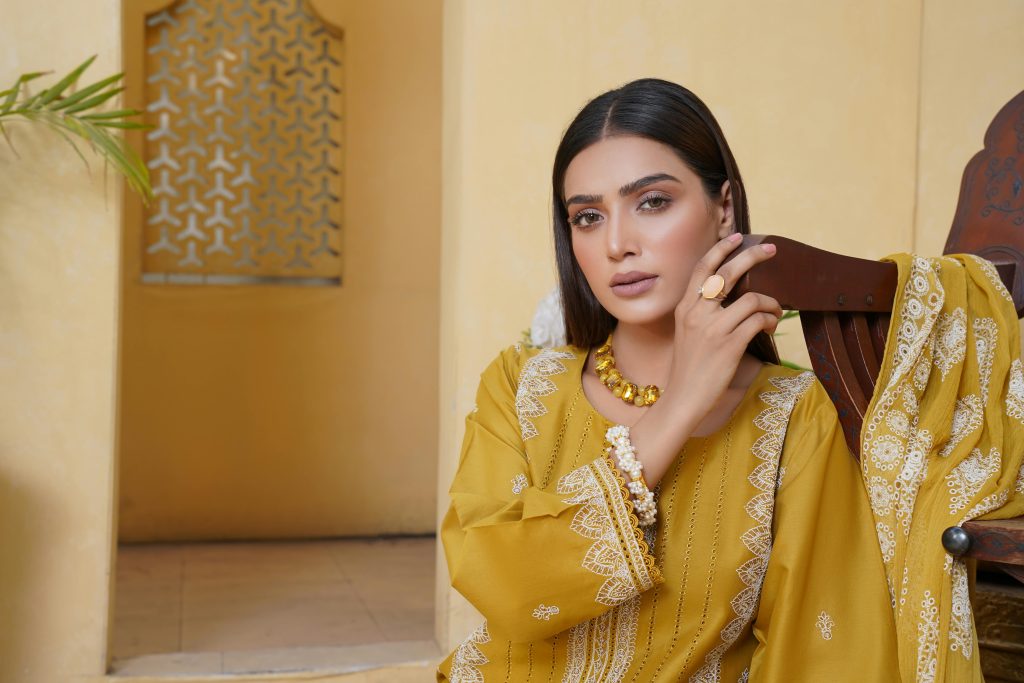 Portrait of a woman in a traditional yellow embroidered dress in Lahore, showcasing cultural fashion.