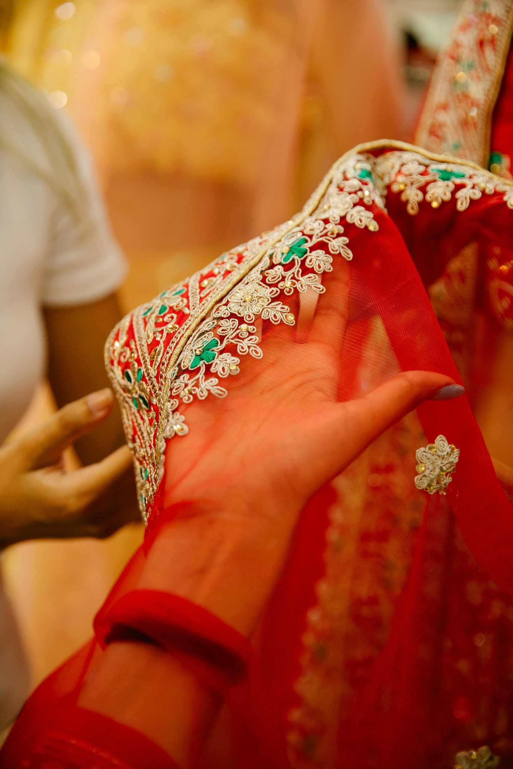 Close-up of a beautifully embroidered red veil fabric being held, showcasing intricate craftsmanship and design.